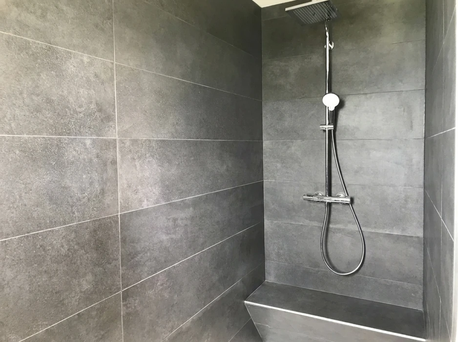 Douche à l'italienne moderne avec parois en grand carrelage grès cérame effet béton anthracite, format 60x120 cm, joints gris fins
