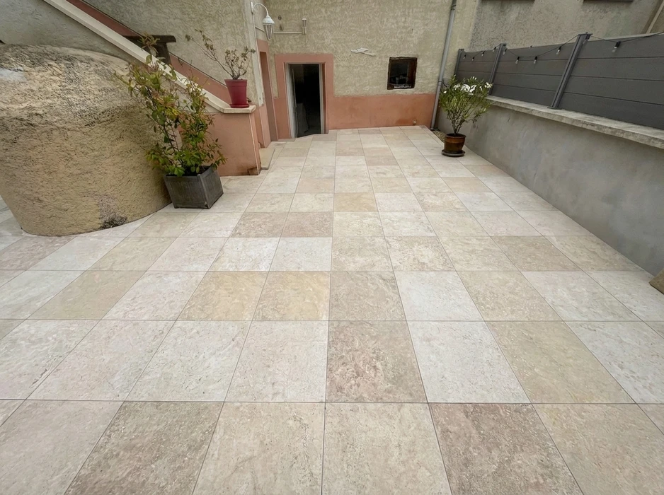 Terrasse extérieure carrelée, encadrée de murs en stuc beige et rose