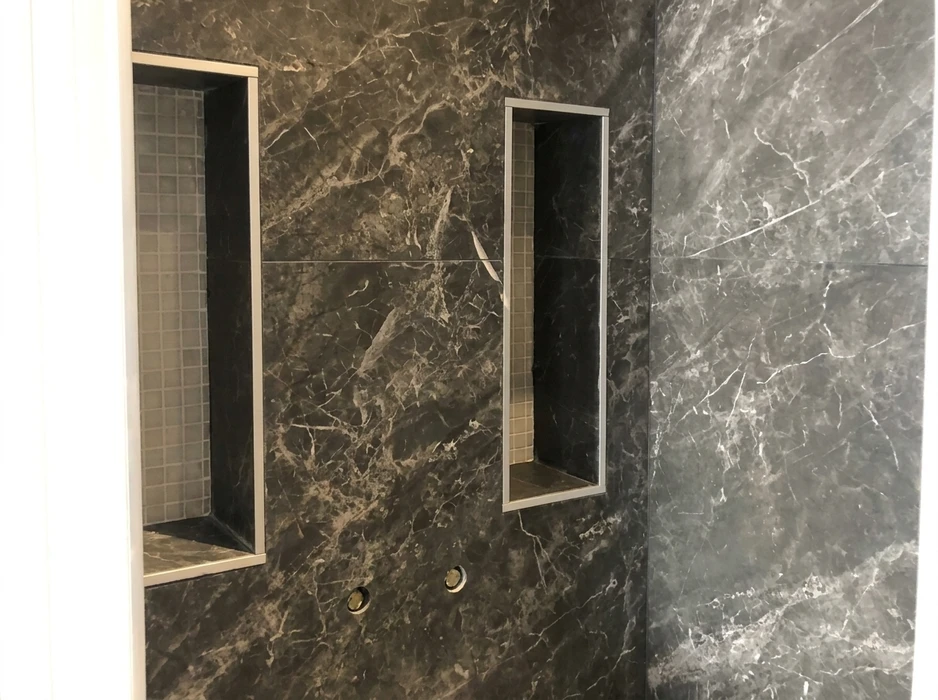 Salle de douche en marbre noir veiné type Marquina ou Saint-Laurent, avec niches encastrées à cadre métallique inox brossé