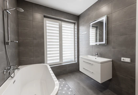 Intérieur de chantier, ouvrier appliquant du mortier-colle avec une truelle crantée sur un mur blanc pour la pose de carrelage