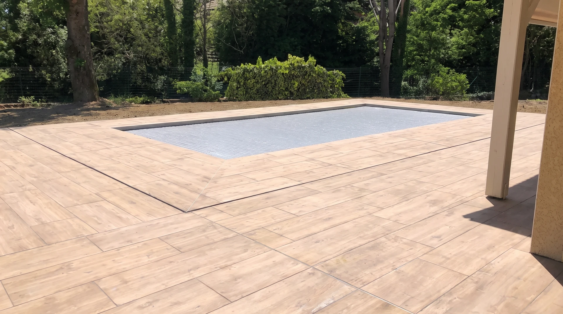 Terrasse extérieure avec piscine rectangulaire couverte d'un volet roulant immergé